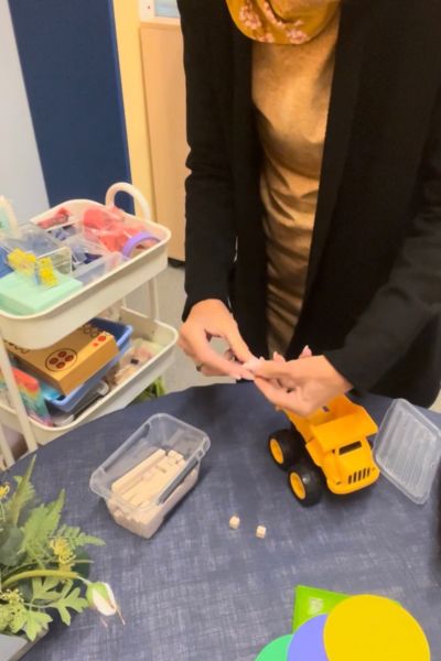 Ein Lerncoach kennt nicht immer die Lösung: Rechenmaterial und ein Spielzeugauto auf einem Tisch, Frau legt mit dem Material eine Menge