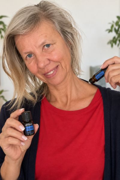 Monatsrückblick August 2026: blonde Frau mit ätherischem Öl "Deep blue" von doterra in der rechten Hand und mit dem Roller dazu auf der Schulter lang rollernd